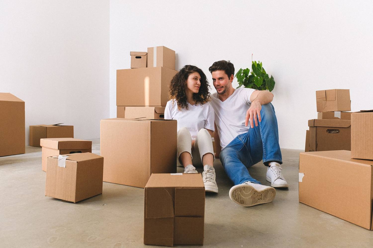 Un couple joyeux assis parmi des boîtes de déménagement dans leur nouvel appartement, planifiant l'avenir ensemble.
